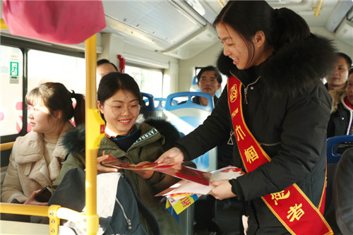 1月22日，在四川省广安火车南站广安区妇联提供的开往城北汽车站的免费“爱心巴士”上，巾帼志愿者正在向返乡民工发放新春大礼包_副本.jpg