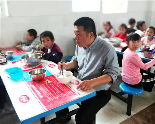 图为永胜学校主持工作的副校长敖文生与学生共同就餐.jpg